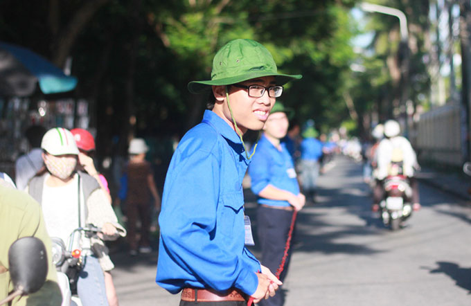 Sinh viên tình nguyện đội nắng căng dây phân làn tuyến đường Nguyễn Bình dẫn vào một điểm thi của trường ĐH Hàng hải - Ảnh: Tiến Thắng