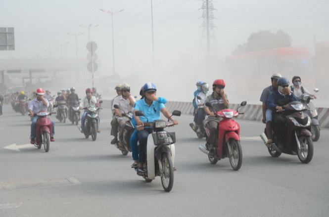 Người dân vừa chạy xe vừa bịt mũi do bụi trên xa lộ Hà Nội sáng 26-10 - Ảnh: Thanh Tùng