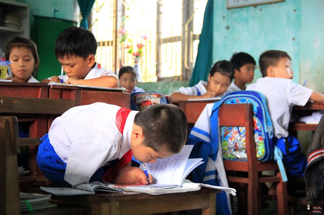 Hà Văn Tài chăm chỉ ngồi học trên lớp và nắn nón viết chữ bằng chân /// Ảnh: Thanh Lộc