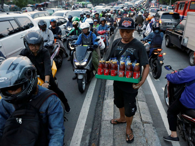 Một thanh niên bán nước dạo vào giờ cao điểm ở Jakarta, Indonesia  /// Ảnh: Reuters