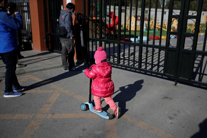 Một bé gái chơi trước cổng một trường mầm non thuộc Tập đoàn giáo dục RYB Education ở Bắc Kinh /// Reuters