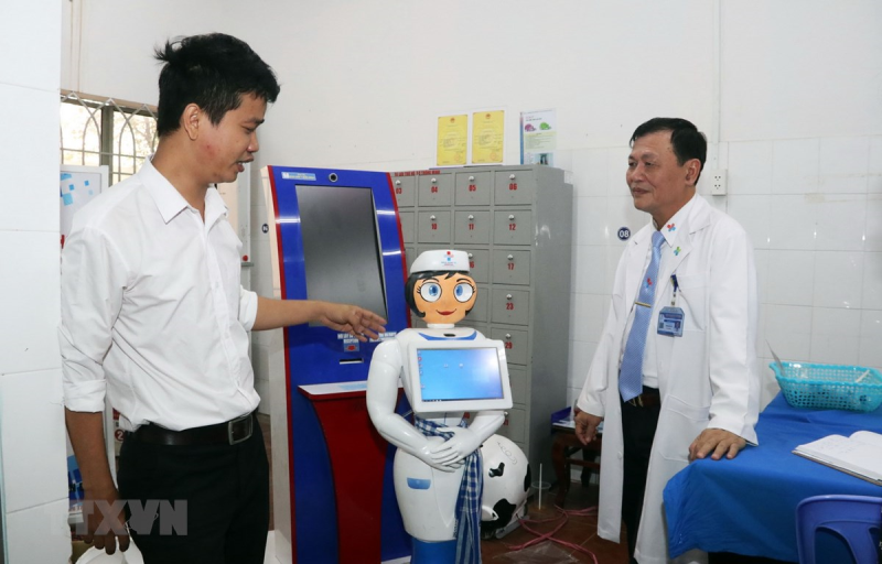 Kỹ sư Võ Hồng Quân, phụ trách Trung tâm Công nghệ thông tin, Bệnh viện Quân dân y miền Đông (trái) giới thiệu robot thông minh Cô Tấm hỗ trợ người bệnh. (Ảnh: Xuân Khu/TTXVN)