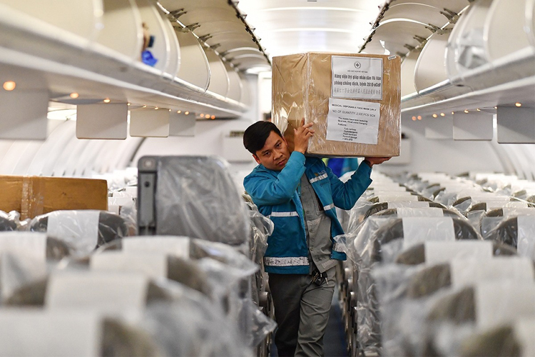 Vận chuyển hàng cứu trợ lên chuyến bay đón công dân Việt từ Vũ Hán về nước. Ảnh: VNA.