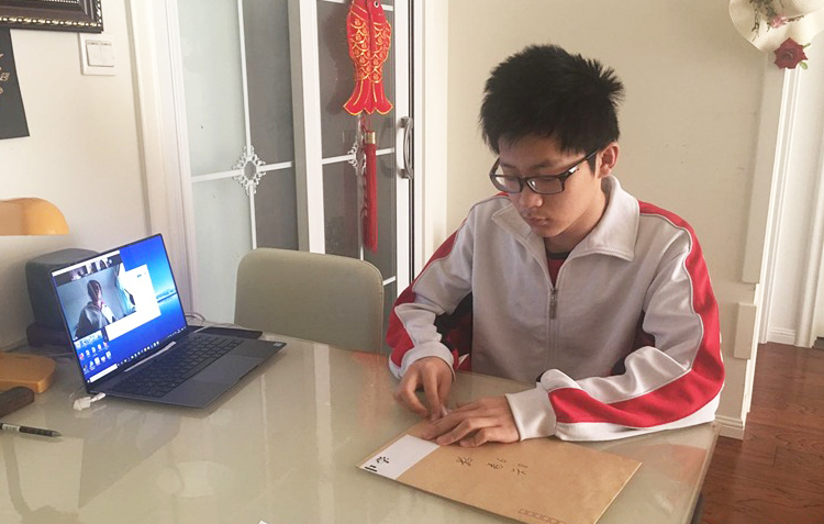 Nam sinh lớp 12, trường THPT Bắc Kinh số 171 làm bài thi thử đại học môn tiếng Trung tại nhà. Ảnh: China Daily.