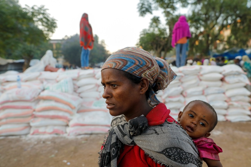 Một người phụ nữ Tigray địu con xếp hàng nhận thực phẩm viện trợ /// REUTERS