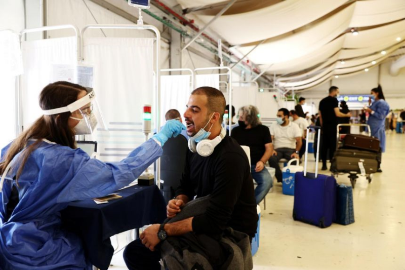 Một nhân viên y tế lấy mẫu tăm bông từ một khách du lịch tại Sân bay Quốc tế Ben Gurion ở Lod, gần Tel Aviv, Israel, vào ngày 13 tháng 10. ẢNH: REUTERS