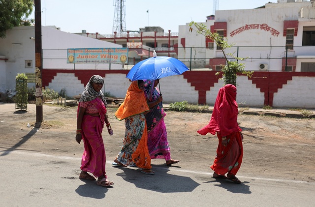 Các nữ cử tri dùng khăn, dù để che nắng khi đi bỏ phiếu tại TP Mathura, bang Uttar Pradesh - Ấn Độ hôm 26-4. Ảnh REUTERS